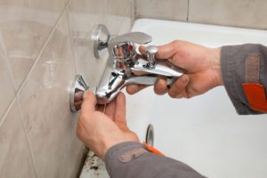 Plumber hands fixing water tap in a bathroom
